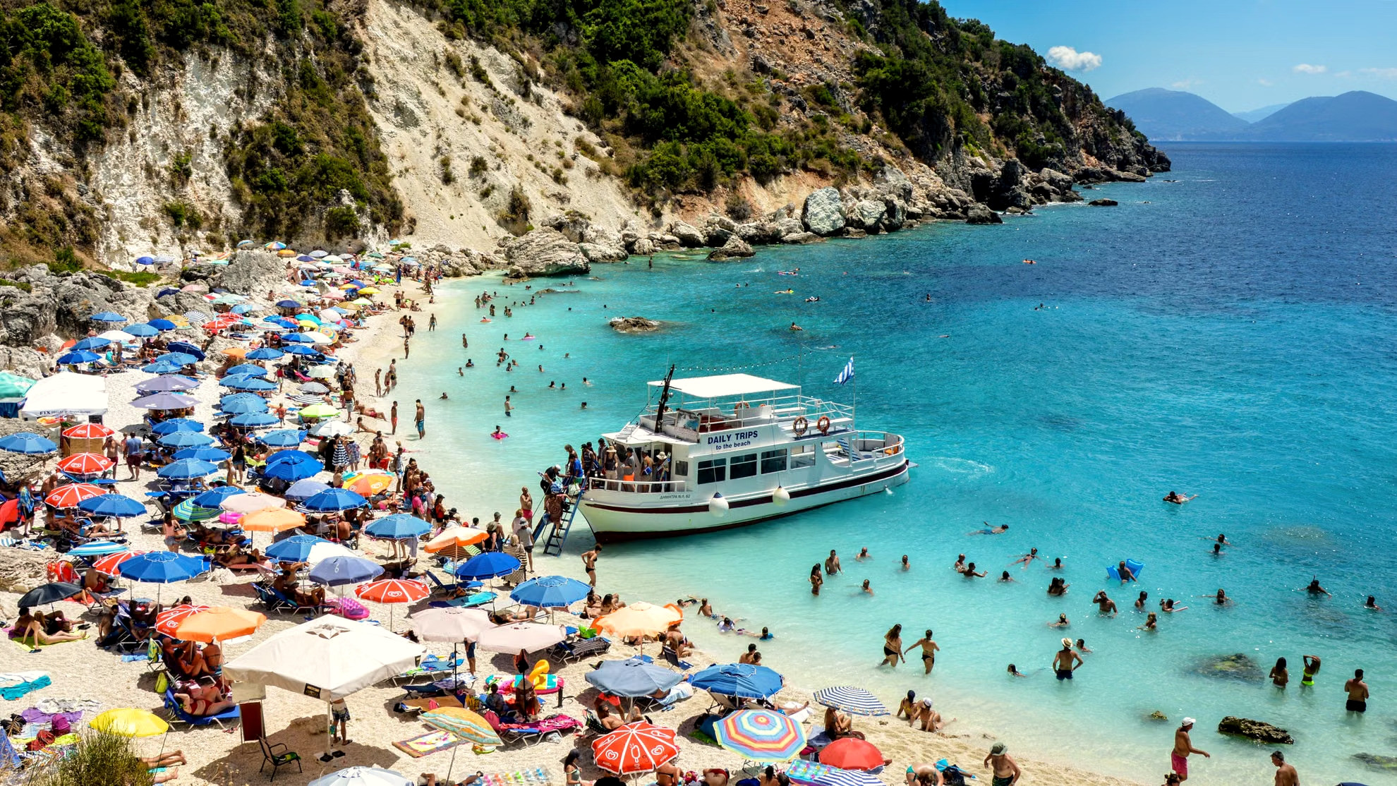 Plage animée et ferry en plein été - Grèce