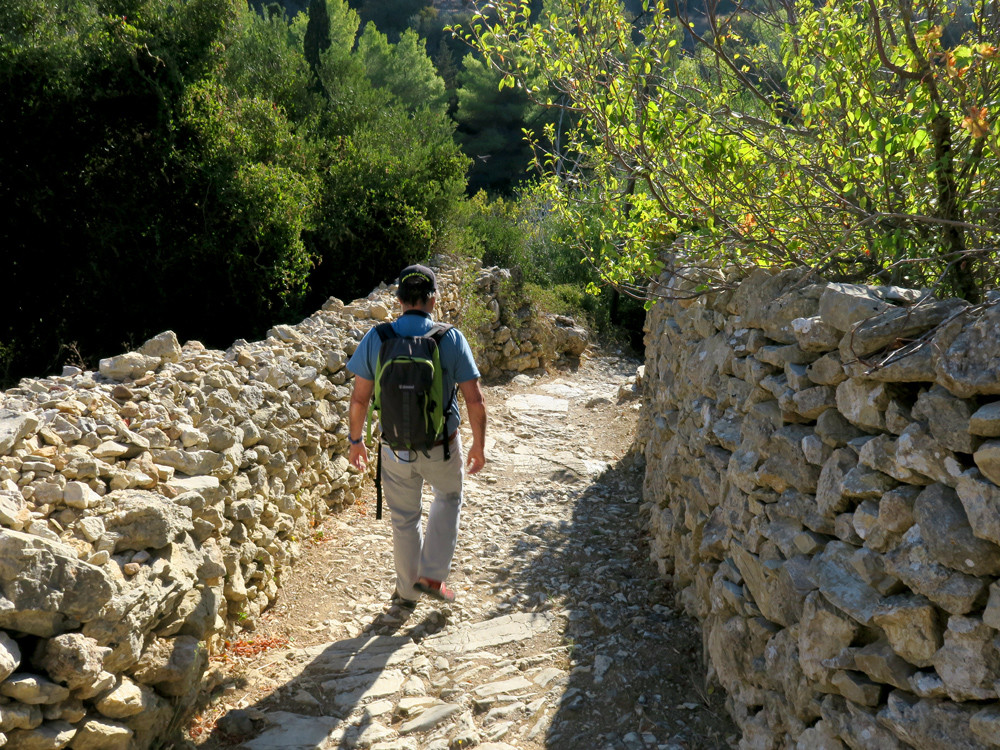 Randonneur sur un chemin bordé de murs en pierres sèches - Milopotamos - Cythère, Grèce