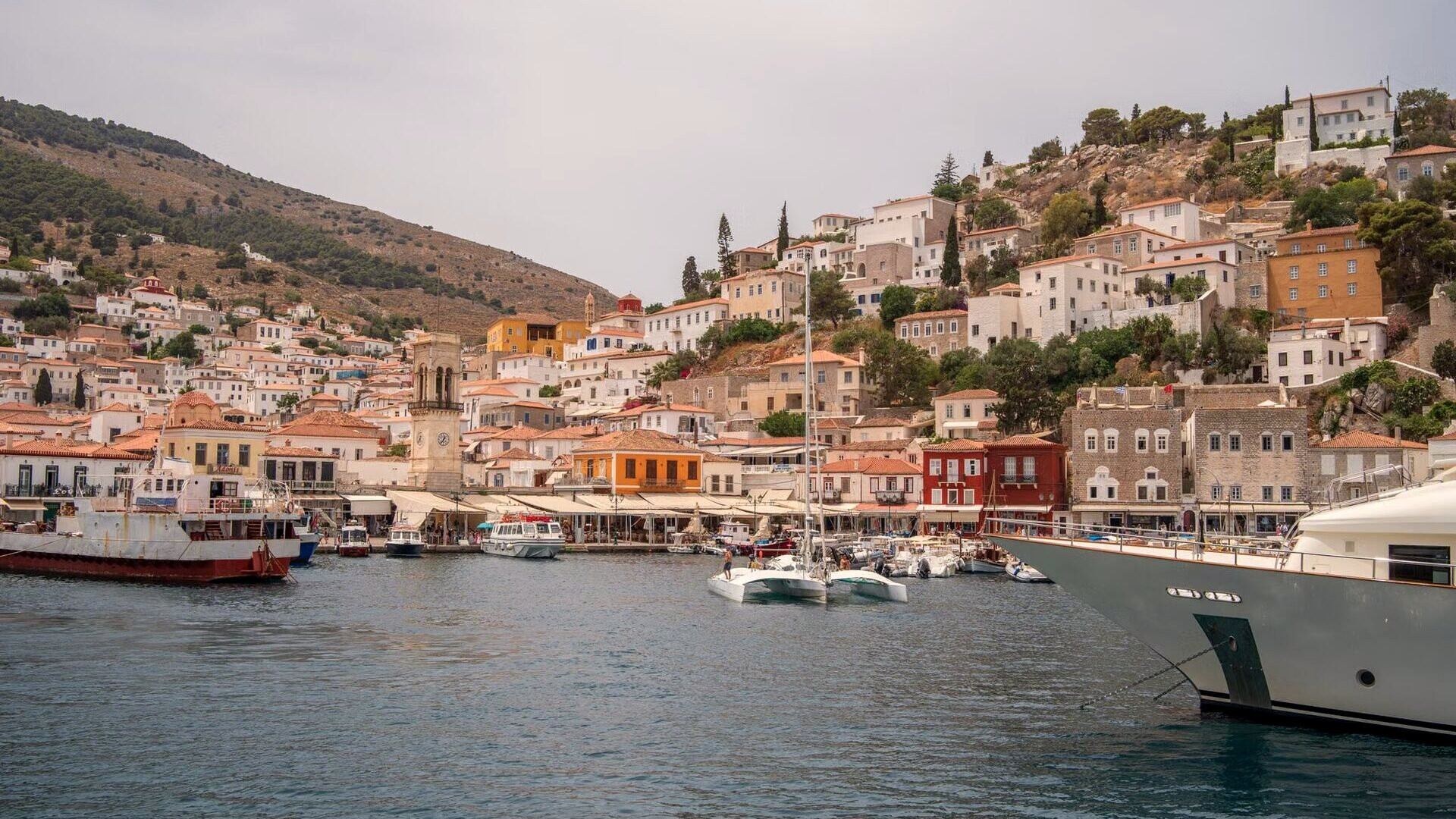 Port en amphithéâtre aux façades de pierre et barques amarrées - Hydra, Grèce