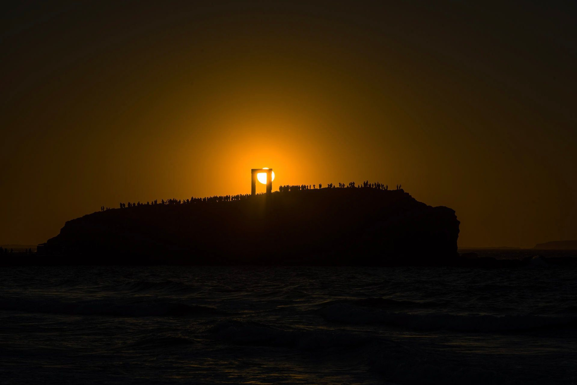 Foule au coucher de soleil sur un îlot rocheux marin - Grèce