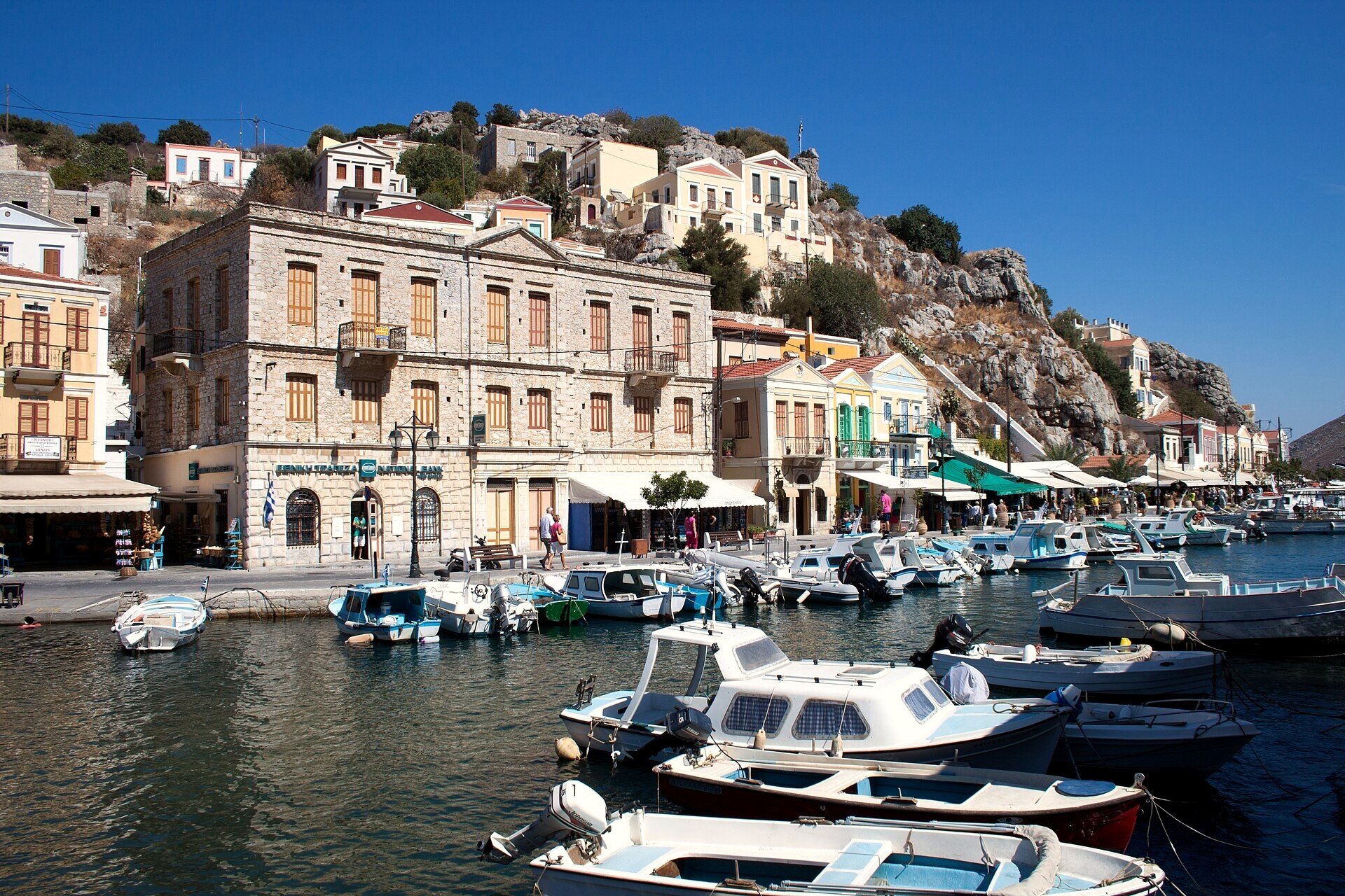 Bateaux amarrés dans le port au pied des maisons néoclassiques - Symi, Grèce
